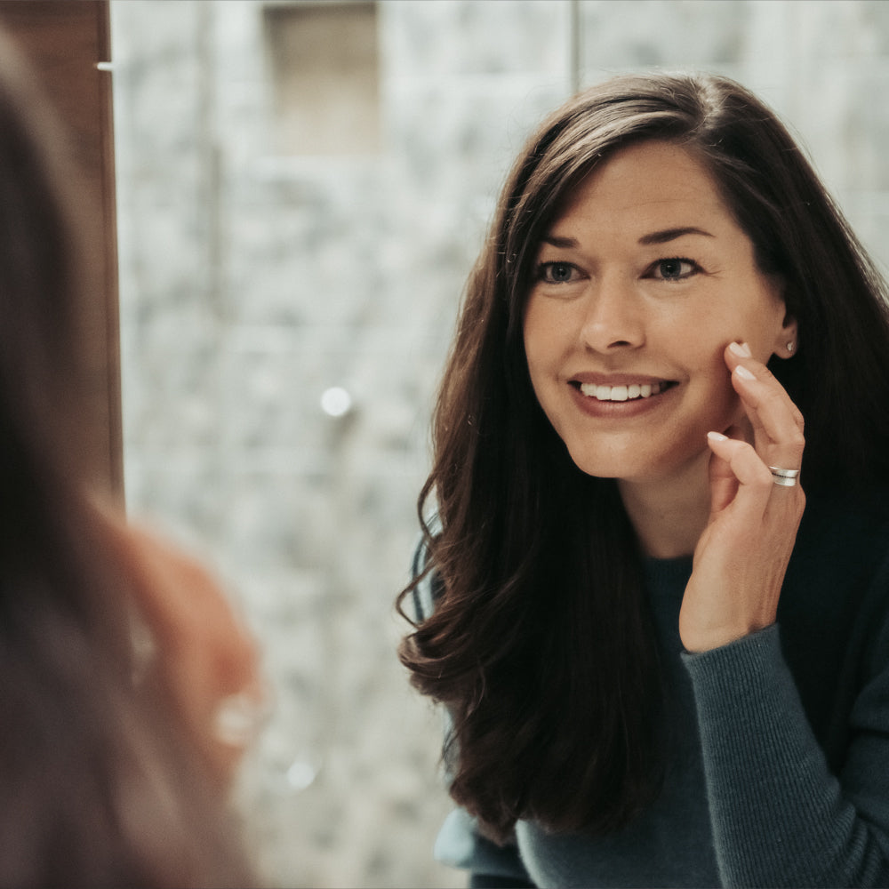 Woman smiling while applying micro-oxygen hydrating night cream to face