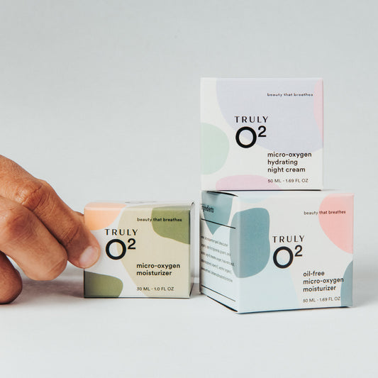Hand reaching for Truly O2 micro-oxygen moisturizer boxes, hydrating night cream, moisturizer, and oil-Free